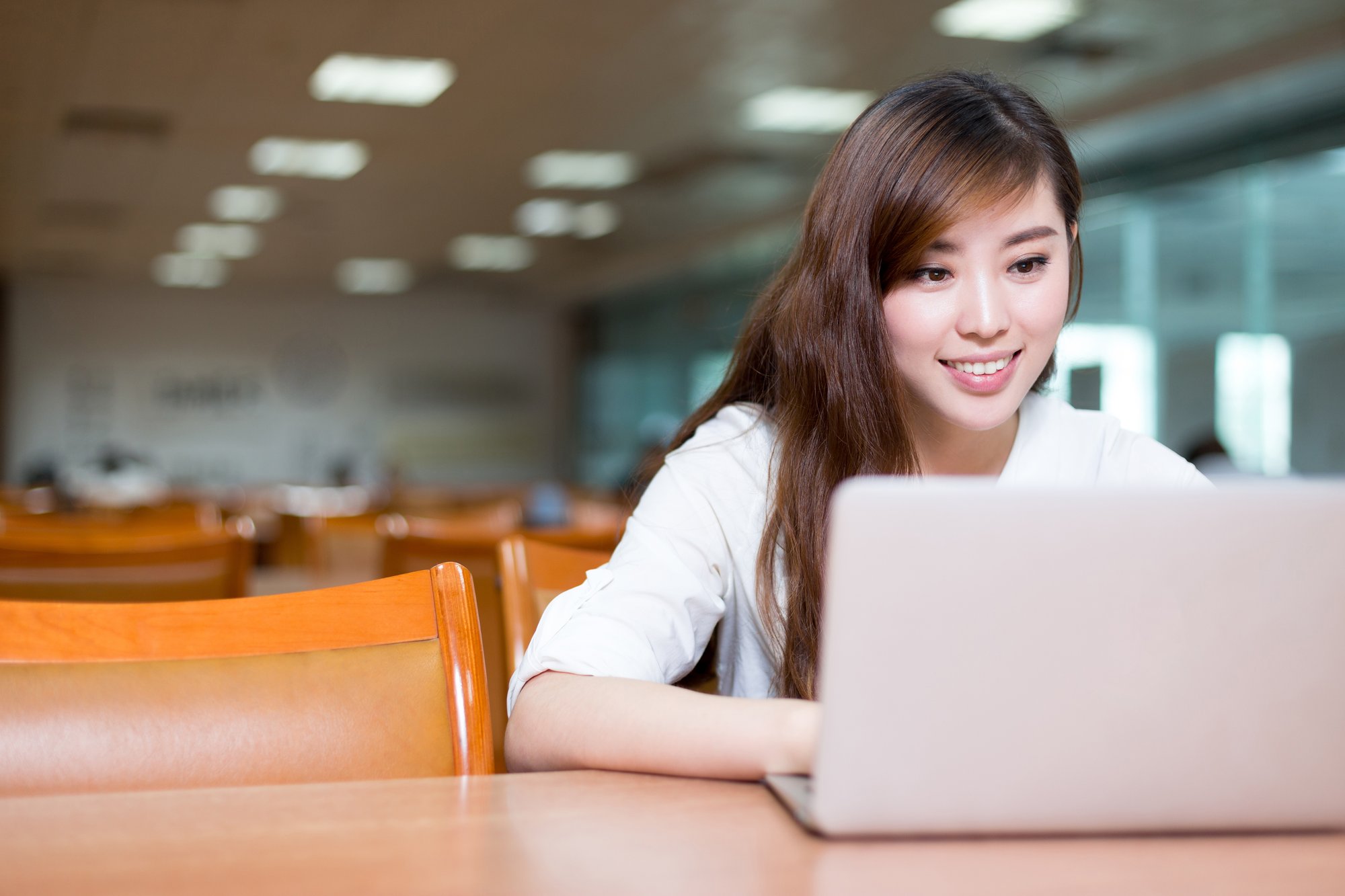 Female student sat at her laptop smiling