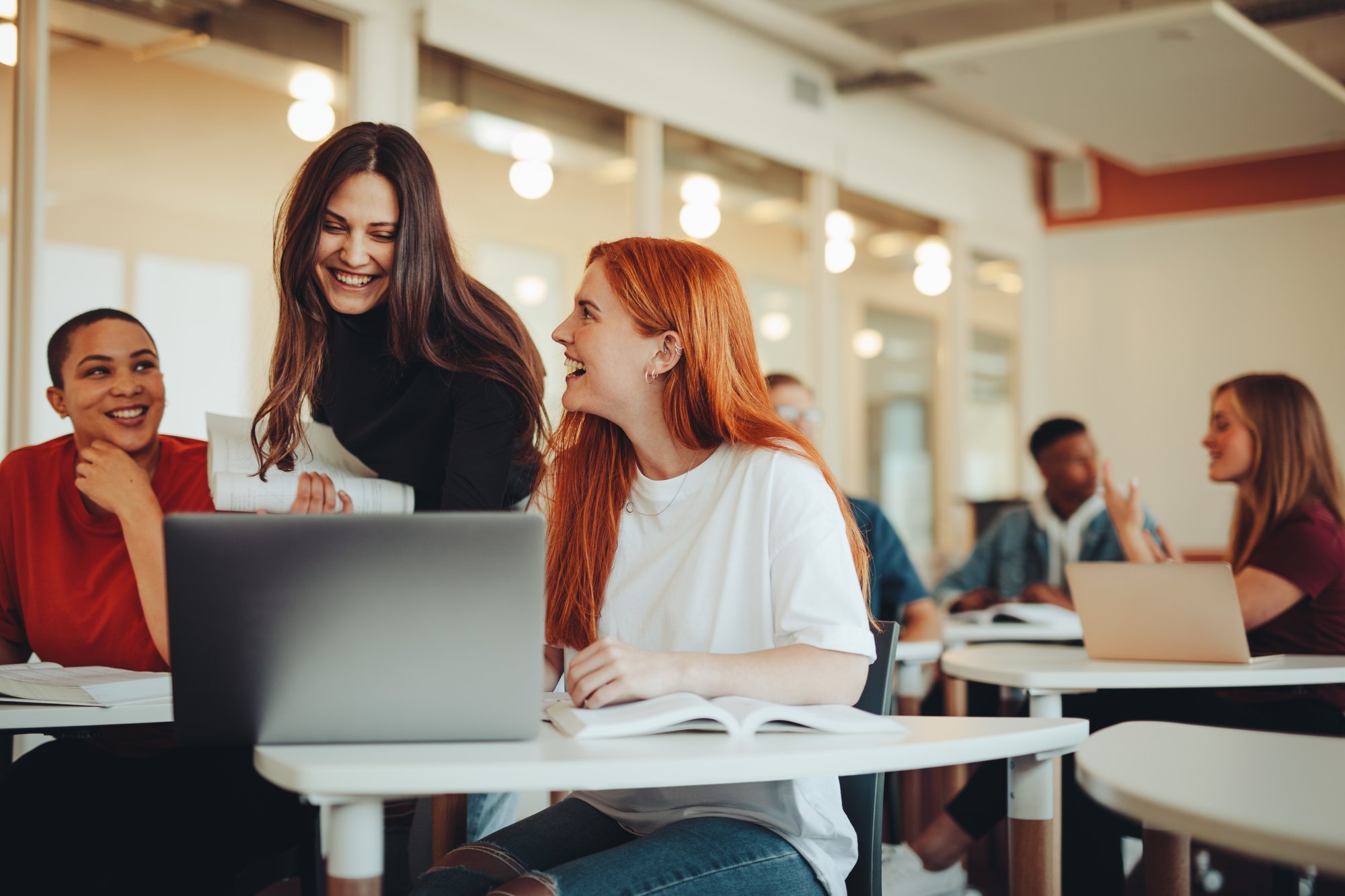 Three female students talking around a laptop Three female students talking around a laptop