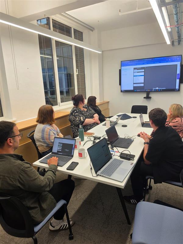 Colleagues sat around a table looking at a large screen